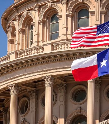 American and Texas state flags flying on the dome of the Texas State Capitol building in Austin