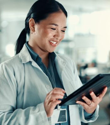 Scientist, woman and typing with tablet at lab for progress report, review and happy for medical research. Person, smile and digital touchscreen with application for results for pharmaceutical study.