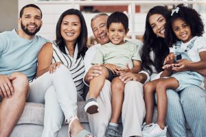 Family, sofa and happy in living room in portrait together in home or on vacation. Children, parents and grandparents love, happiness and smile while on holiday, in hotel or house in Houston, Texas.