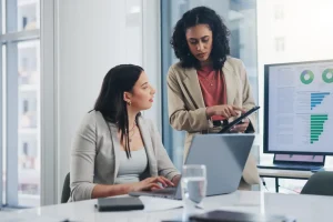 Business meeting, data analytics or women with graph presentation in office for tablet, idea or laptop collaboration. Chart, analysis or accounting team brainstorming economy, inflation or solution.